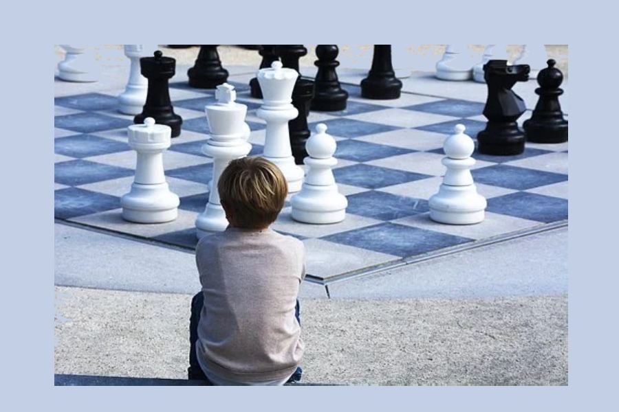 chłopiec siedziący przed wielką szachownicą