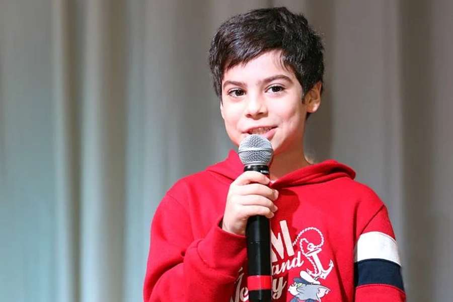 chłopiec w czerwonej bluzie, trzymający mikrofon