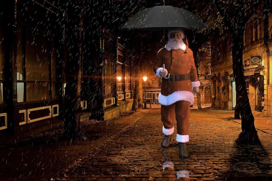 Zdjęcie przedstawia Mikołaja z parasolem w deszczowy wieczór