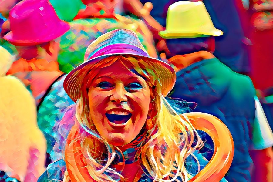 Zdjęcie przedstawia roześmianą twarz kobiety w kolorowym kapeluszu