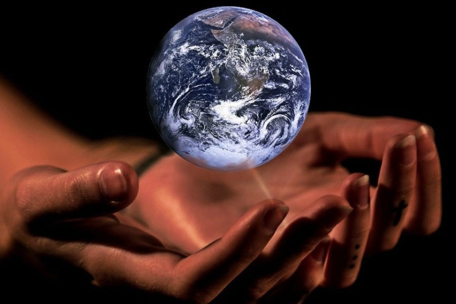 Zdjęcie przedstawia planetę Ziemię, unoszącą się nad ludzkimi dłońmi, które okalają ją w geście jej ochrony.