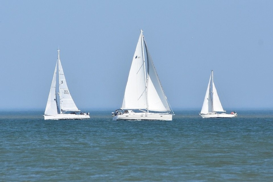 trzy jachty żaglowe płynące po morzy na tle zamglonego horyzontu