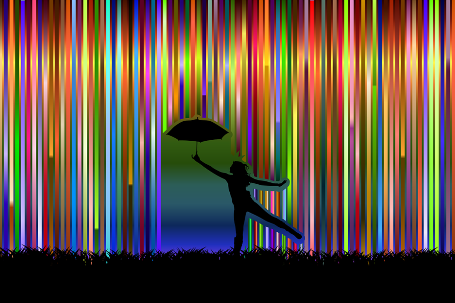 Zdjęcie przedstawia postać tancerza z parasolką w ręku na tle kolorowych pionowych tęczowych pasków.