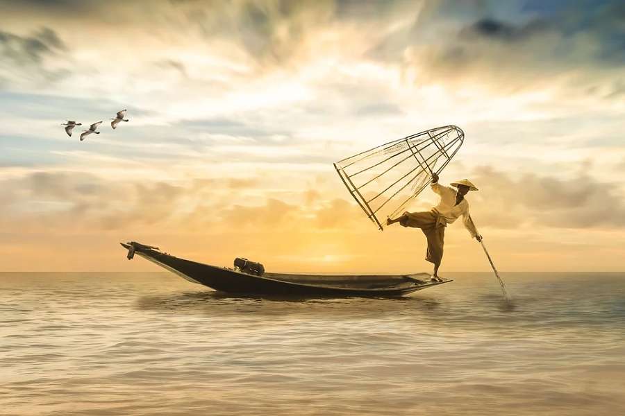 zdjęcie przedstawia japońskiego rybaka łowiącego na morzu.