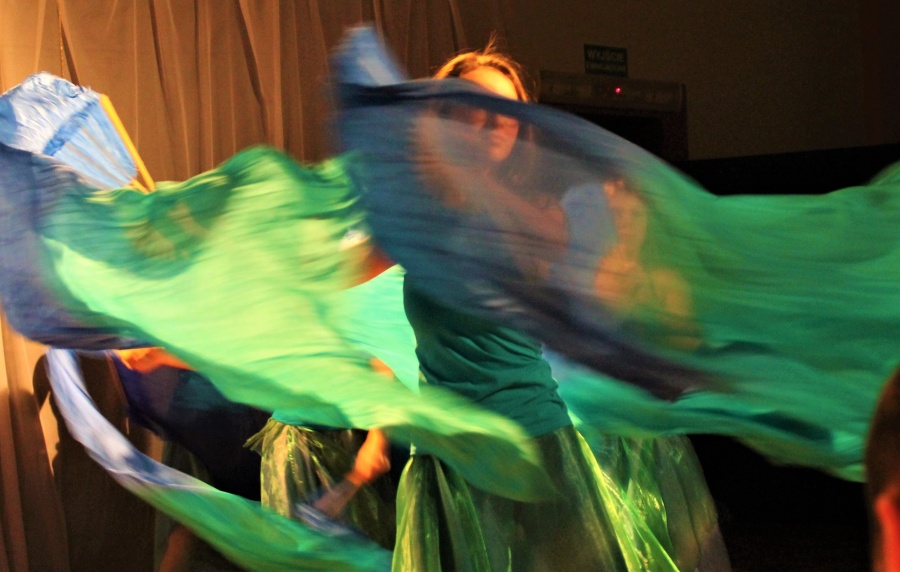Kobieta tańcząca z rekwizytem wachlarzowoalem turkusowo-niebiesko-zielonym i imitującym wodę.