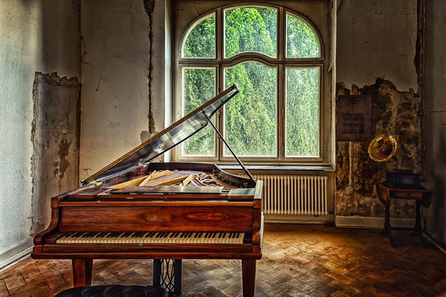fortepian sotjący na środku zniszczonego pokoju