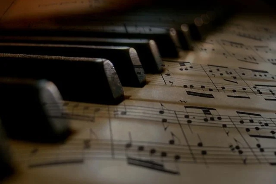 Na zdjęciu widać klawiaturę fortepianu całą pokrytą nutami.
