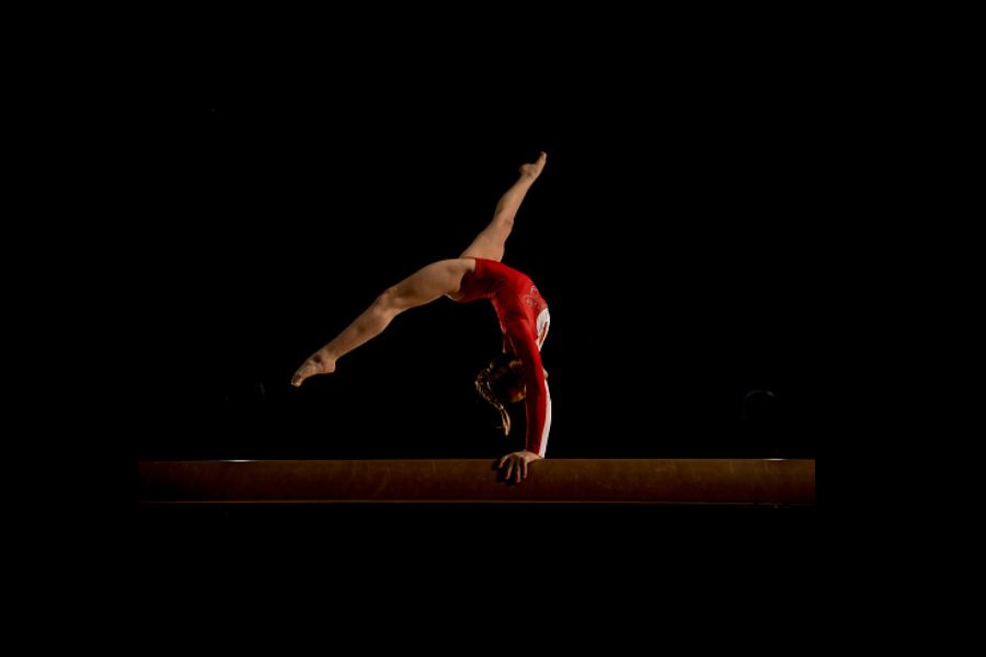 gimnastyczka w czerwonym stroju robi przejście akrobatyczne w przód