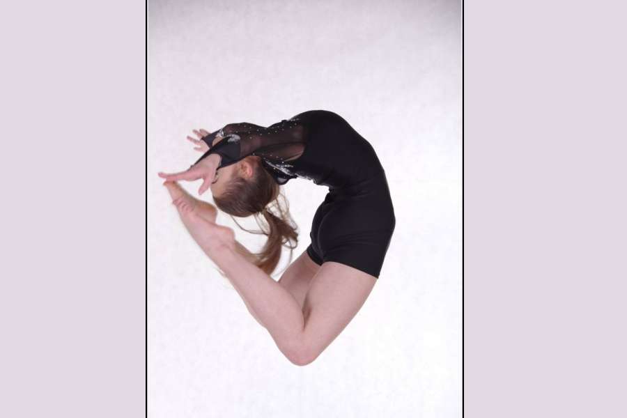 tancerka w czarnym kostiumie, wykonująca skok tzw. kółeczko