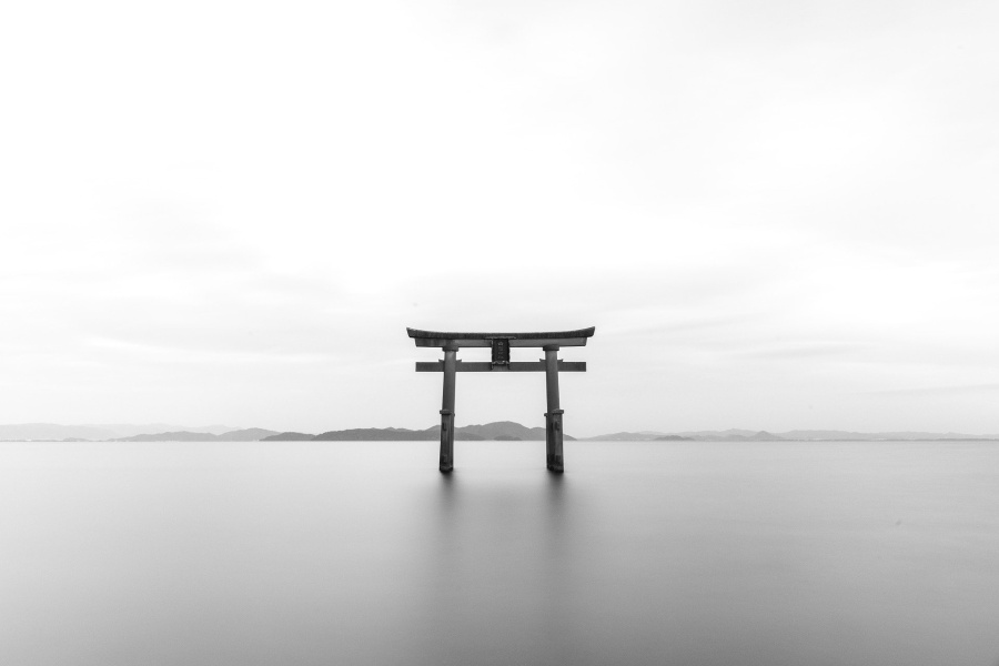 Japońska brama Tori na tle stalowego nieba i stojąca w jeziorze o szarym kolorze