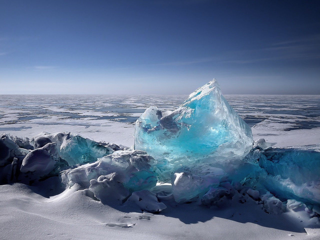 Niebieskawa bryła lodu wystaje zalodzonego akwenu