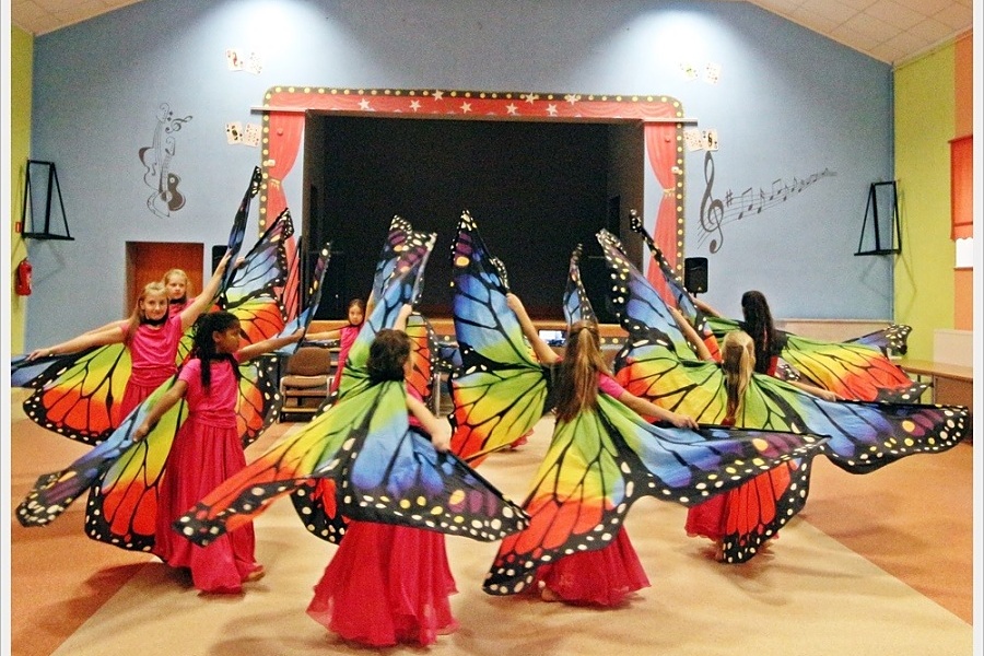 Tańczące w kole dziewczęta ze skrzydłami motyla